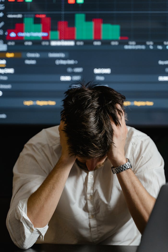 Businessman in white shirt stressed with declining stock prices on the screen.